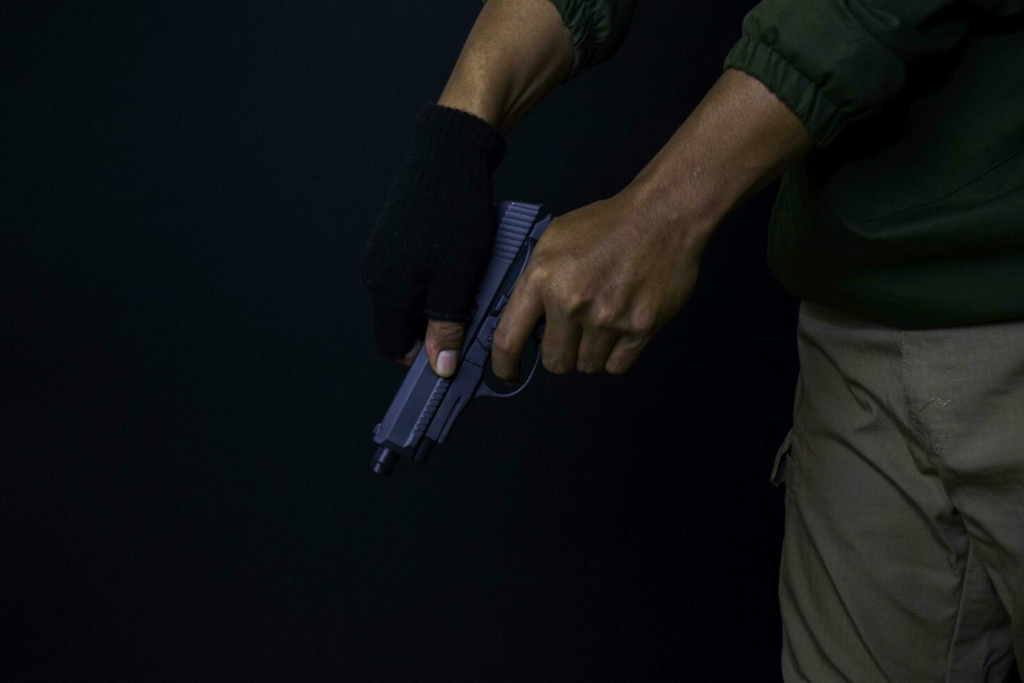 asiático hombre sostiene un pistola. pistola en su mano. delicado disparo su objetivo aislado en negro antecedentes. foto