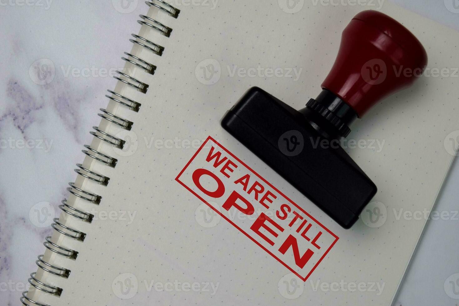Red Handle Rubber Stamper and We Are Still Open text isolated on the table. photo