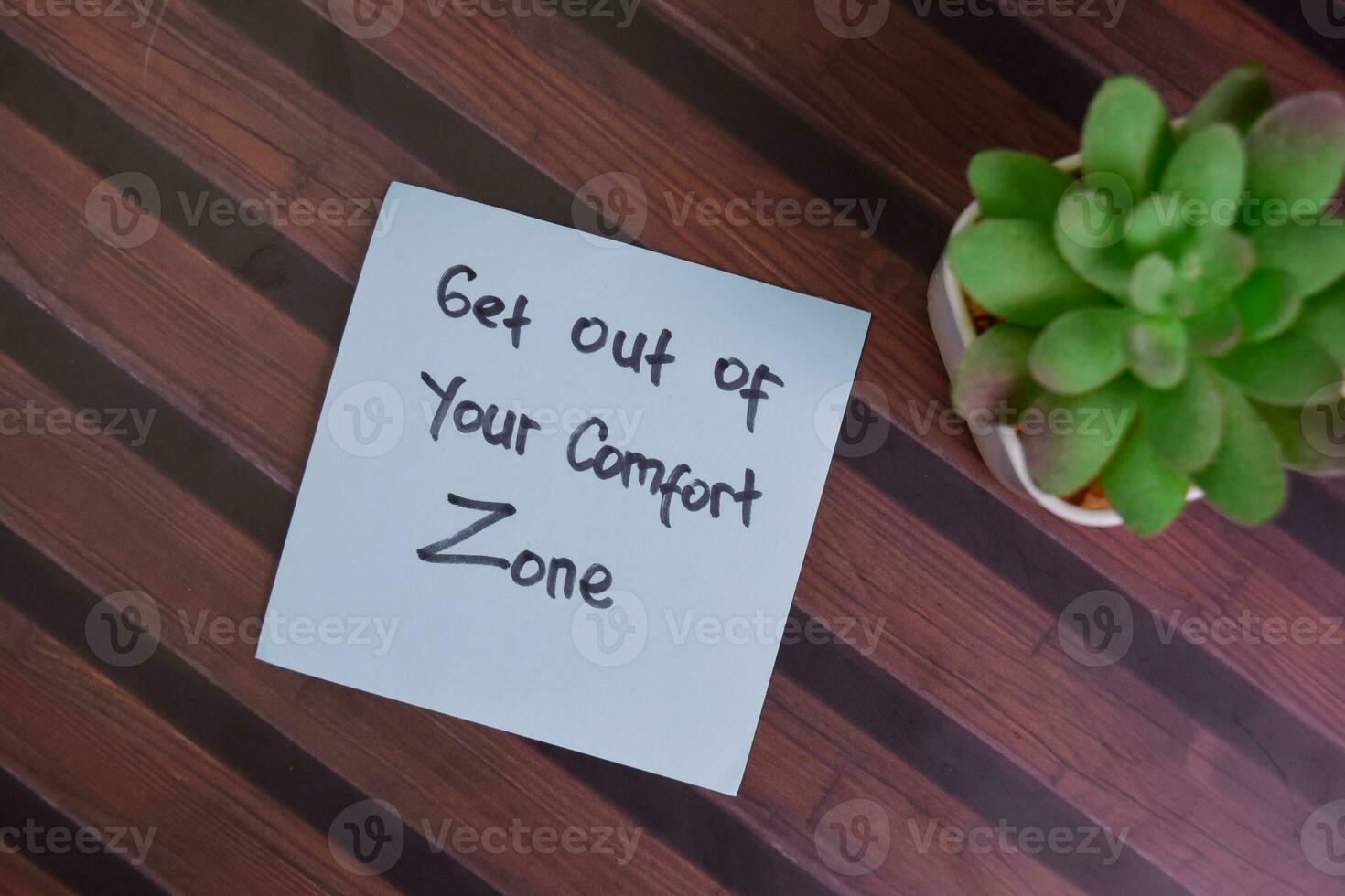 Get Out of Your Comfort Zone write on sticky notes isolated on Wooden Table. photo