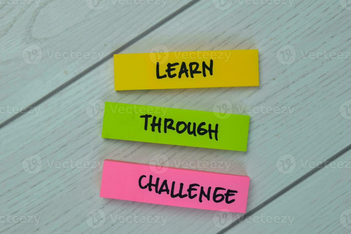 Learn - Through - Challenge write on sticky notes isolated on Wooden Table. photo