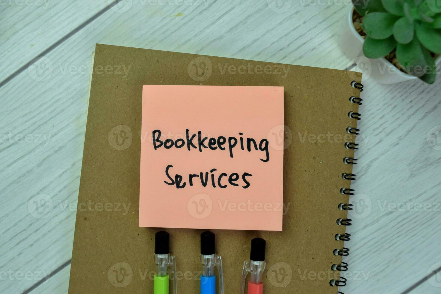 Concept of Bookkeeping Services write on sticky notes isolated on Wooden Table. photo