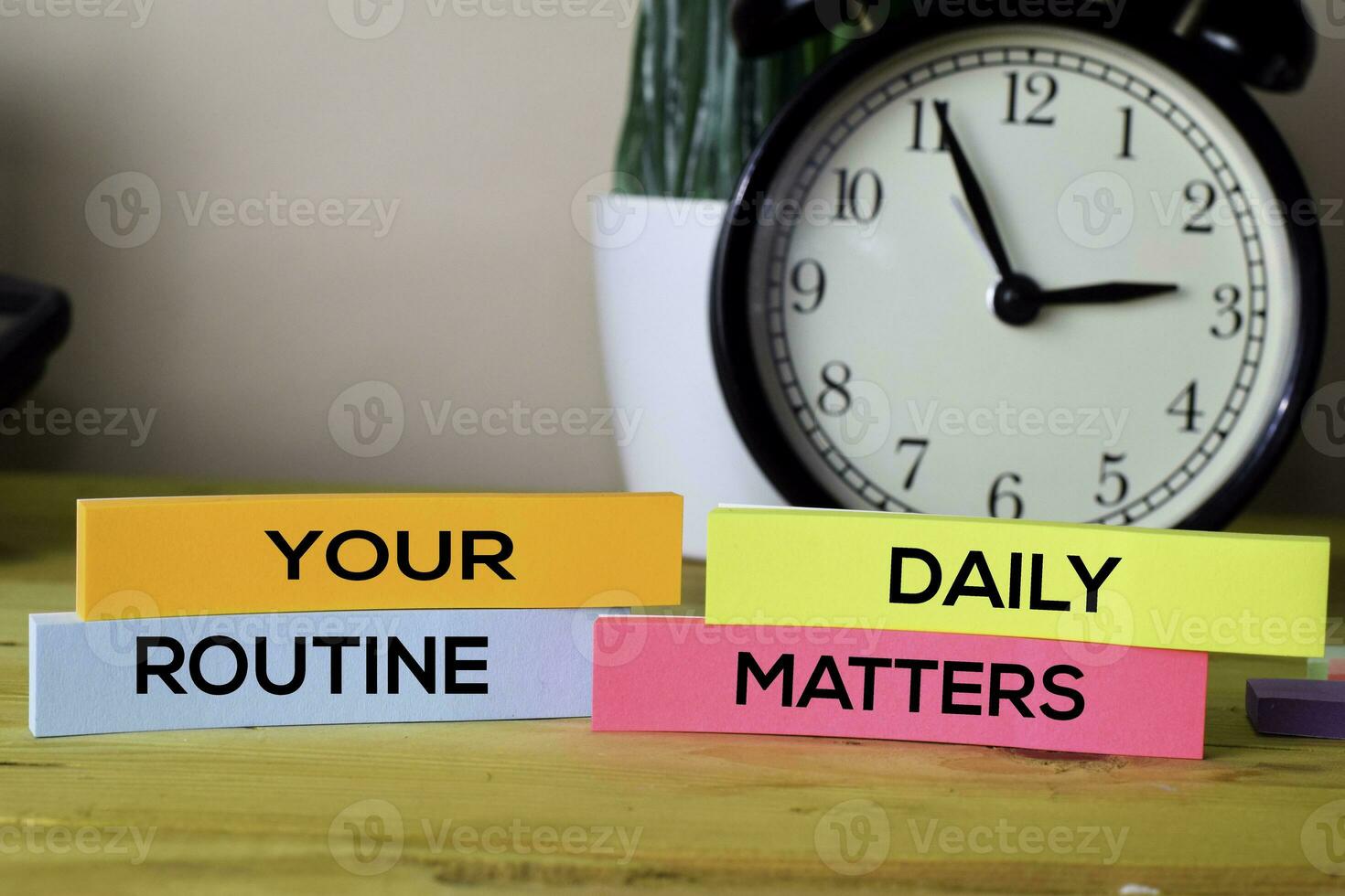 Your Daily Routine Matters. Handwriting on sticky notes in clothes pegs on wooden office desk photo