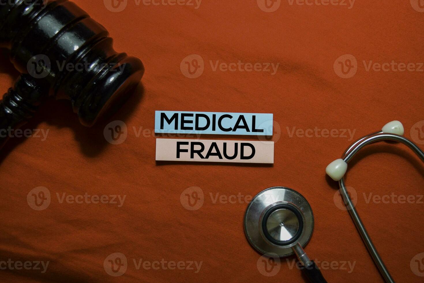 Medical Fraud text on sticky notes with stethoscope and gavel isolated on office desk. photo