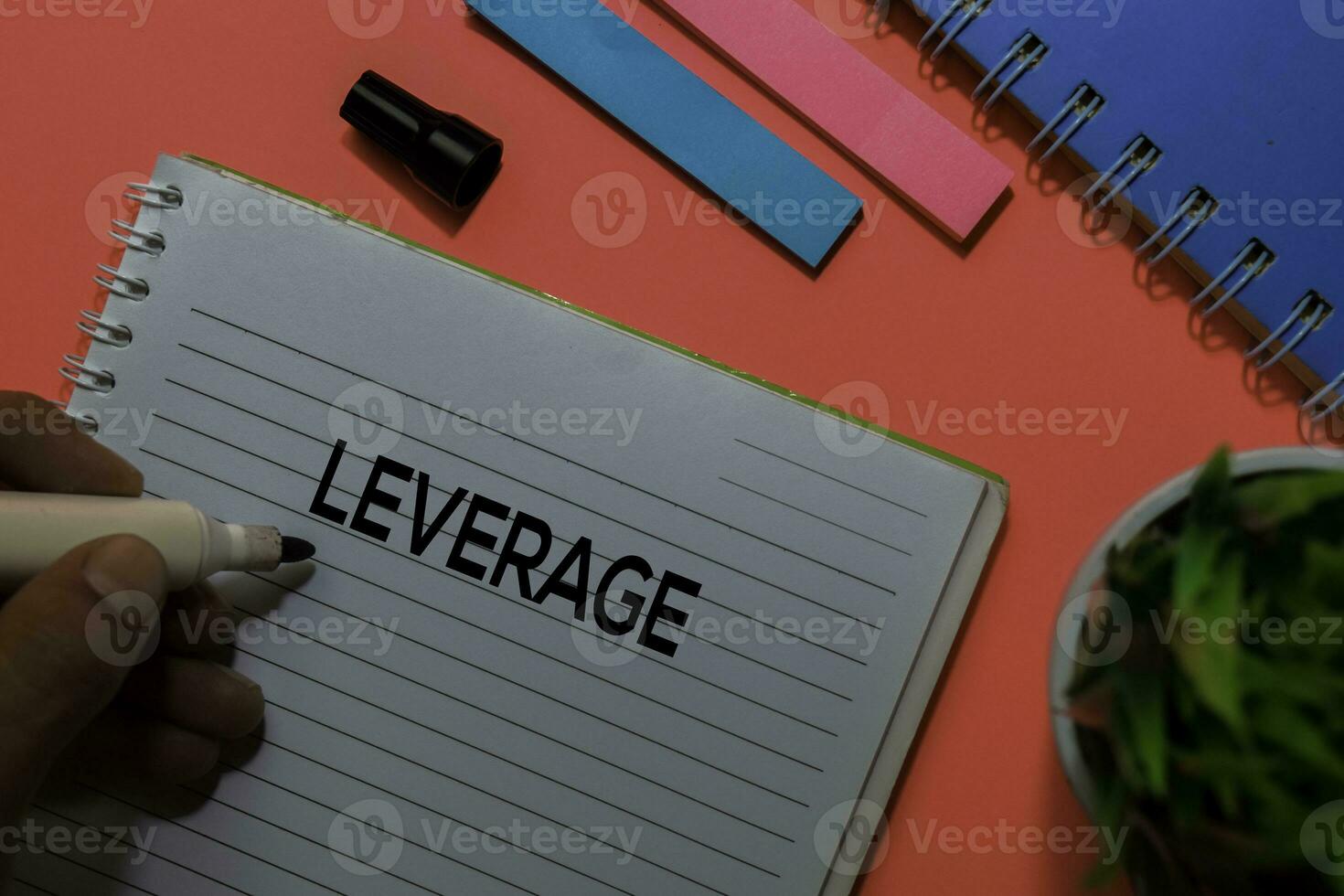 Leverage write on book. Isolated on pink table background photo