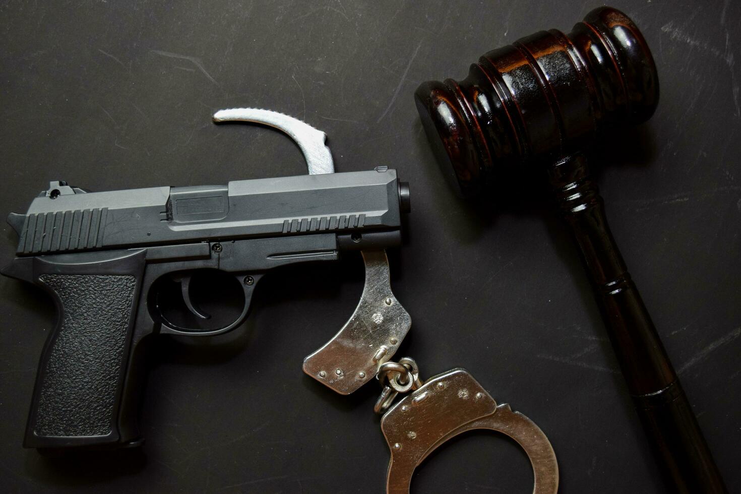 gun, handcuffs and black gavel isolated on black background. Justice and law concept photo