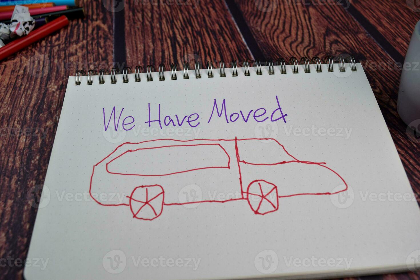 We Have Moved write on a book and drawing car Isolated on wooden table background photo