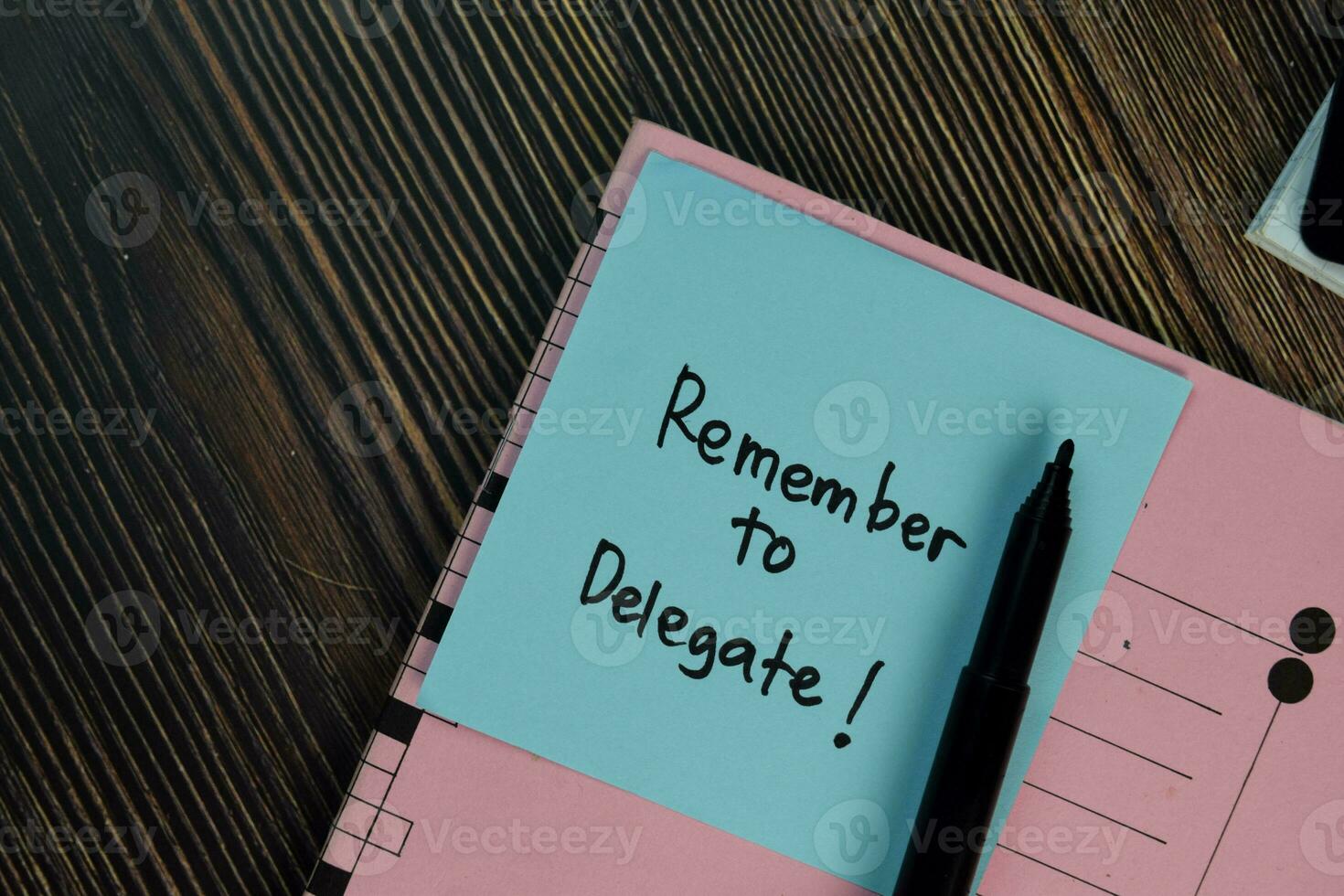 Remember to Delegate write on sticky notes isolated on Wooden Table. photo
