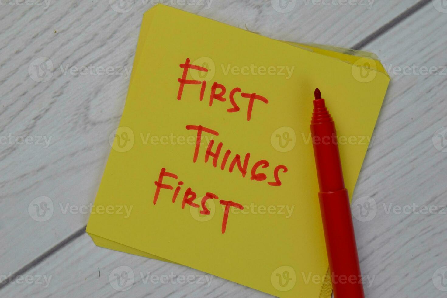 First Things First write on sticky notes isolated on Wooden Table. photo
