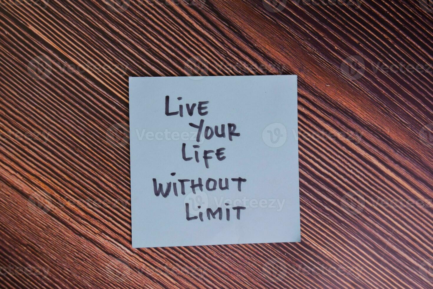 Live Your Life Without Limit write on sticky notes isolated on Wooden Table. photo