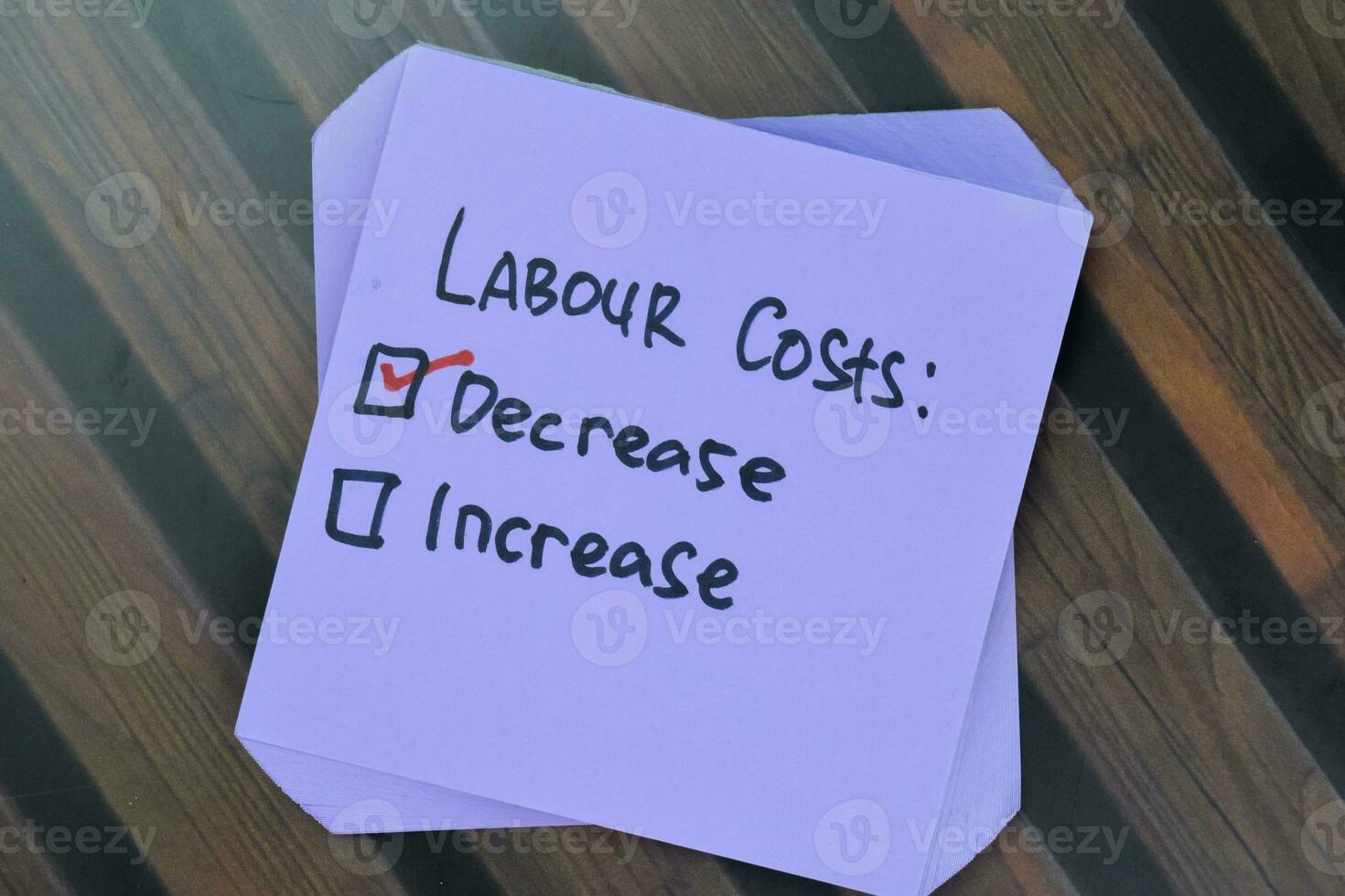 Concept of Labour Costs. Decrease or Increase write on sticky notes isolated on Wooden Table. photo