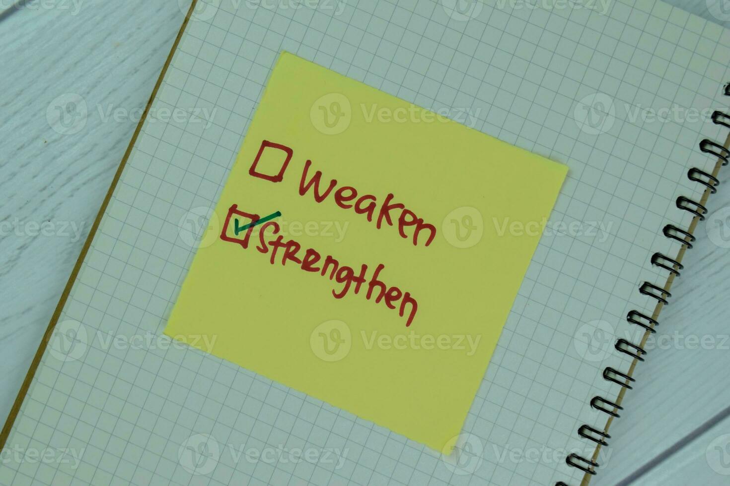Concept of Strengthen versus Weaken write on sticky notes isolated on Wooden Table. photo