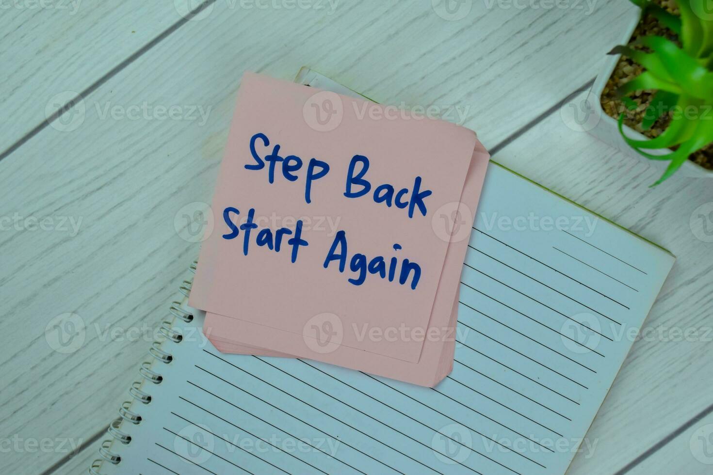 Concept of Step Back Start Again write on sticky notes isolated on Wooden Table. photo