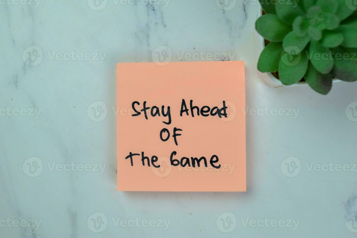 Concept of Stay Ahead Of The Game write on sticky notes isolated on Wooden Table. photo