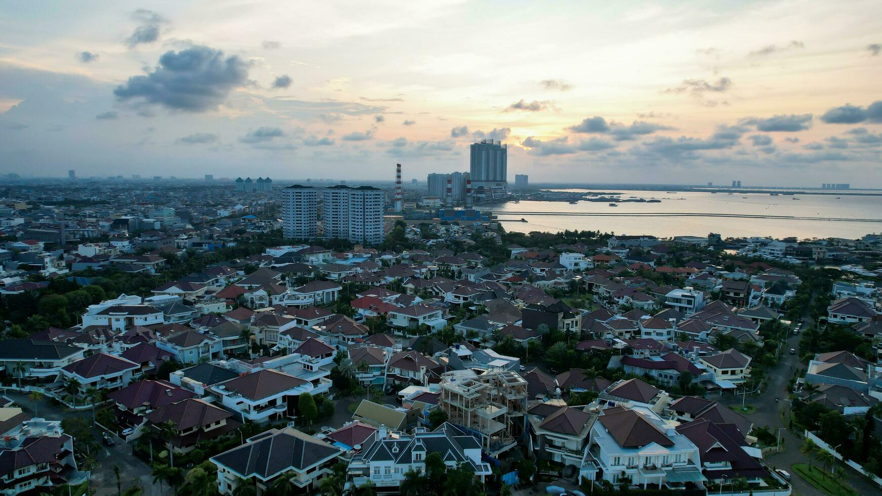 Aerial view of the Bright spring cityscape of Pluit port. Colorful sunset view of Jakarta, Indonesia. Beautiful Jakarta seascape. Traveling concept background. Jakarta, Indonesia, September 16, 2022 photo