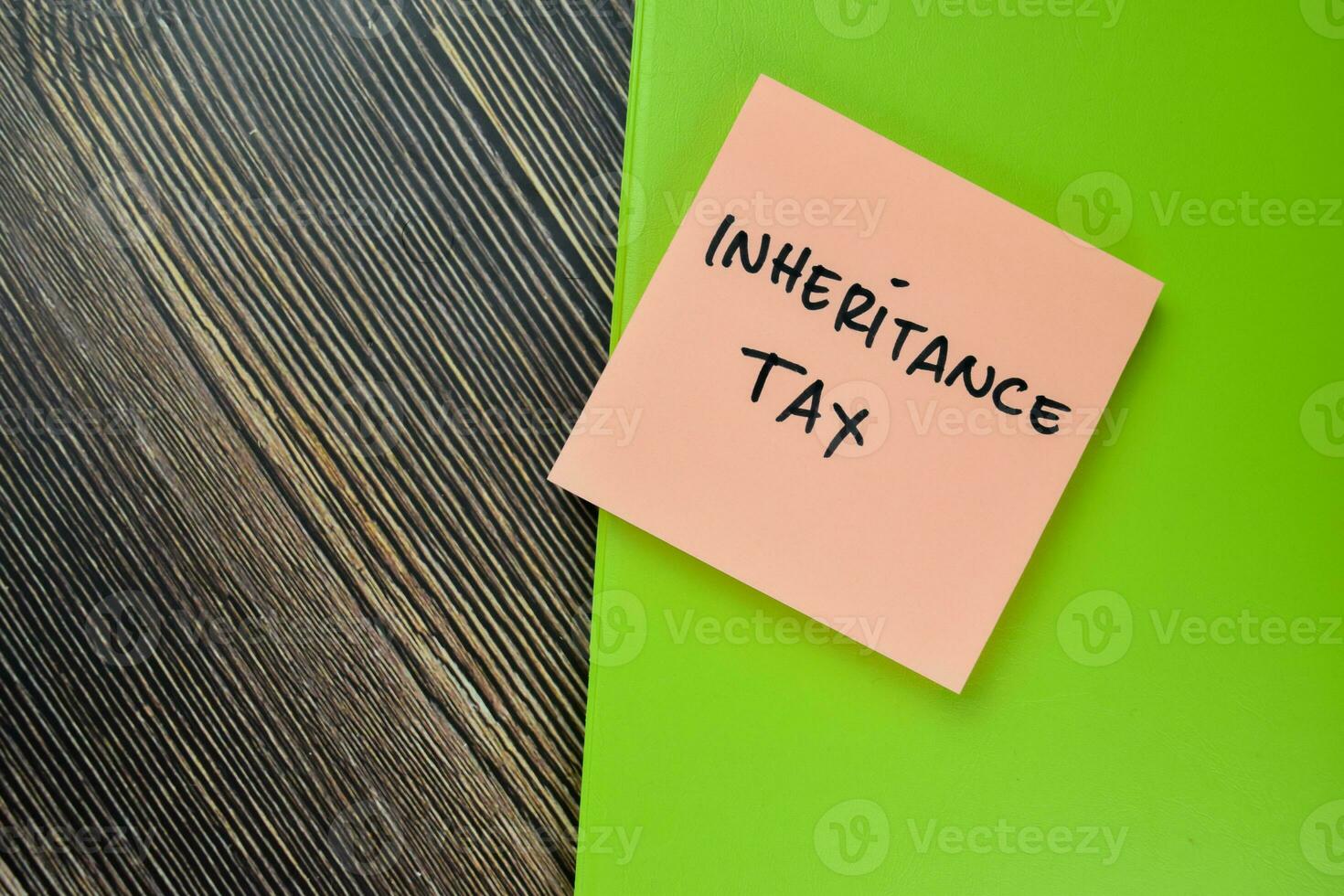 Concept of Inheritance Tax write on sticky notes isolated on Wooden Table. photo