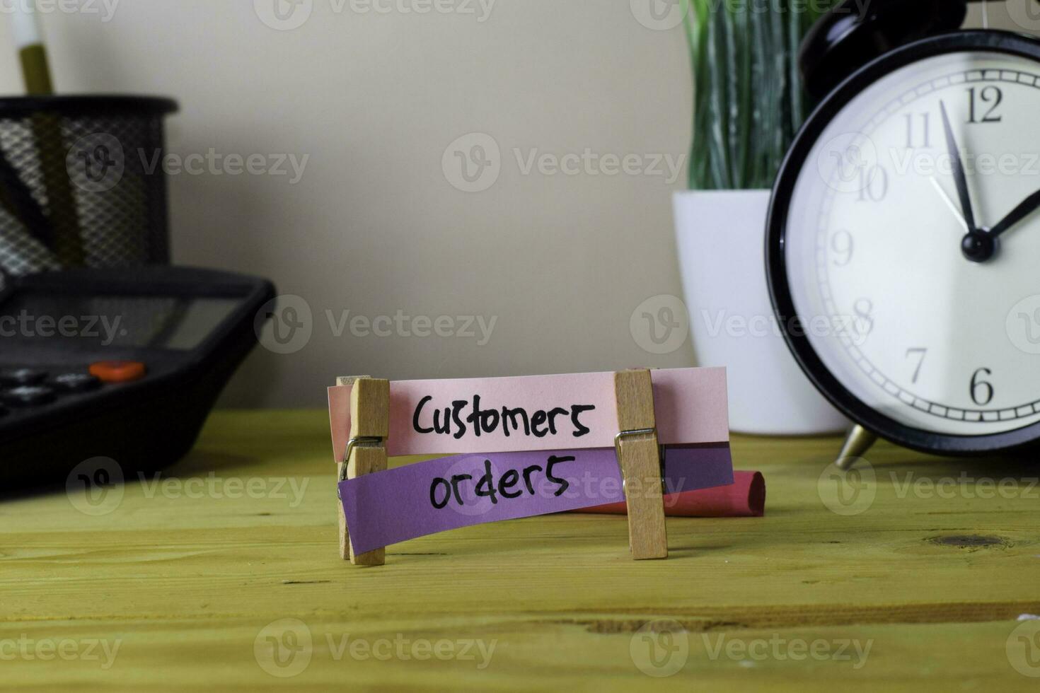 Customers and Orders. Handwriting on sticky notes in clothes pegs on wooden office desk photo