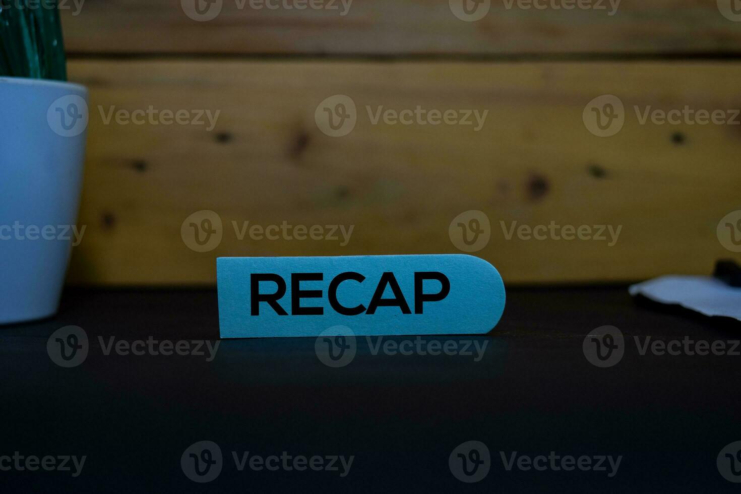 Recap write on a sticky note isolated on wooden background. photo