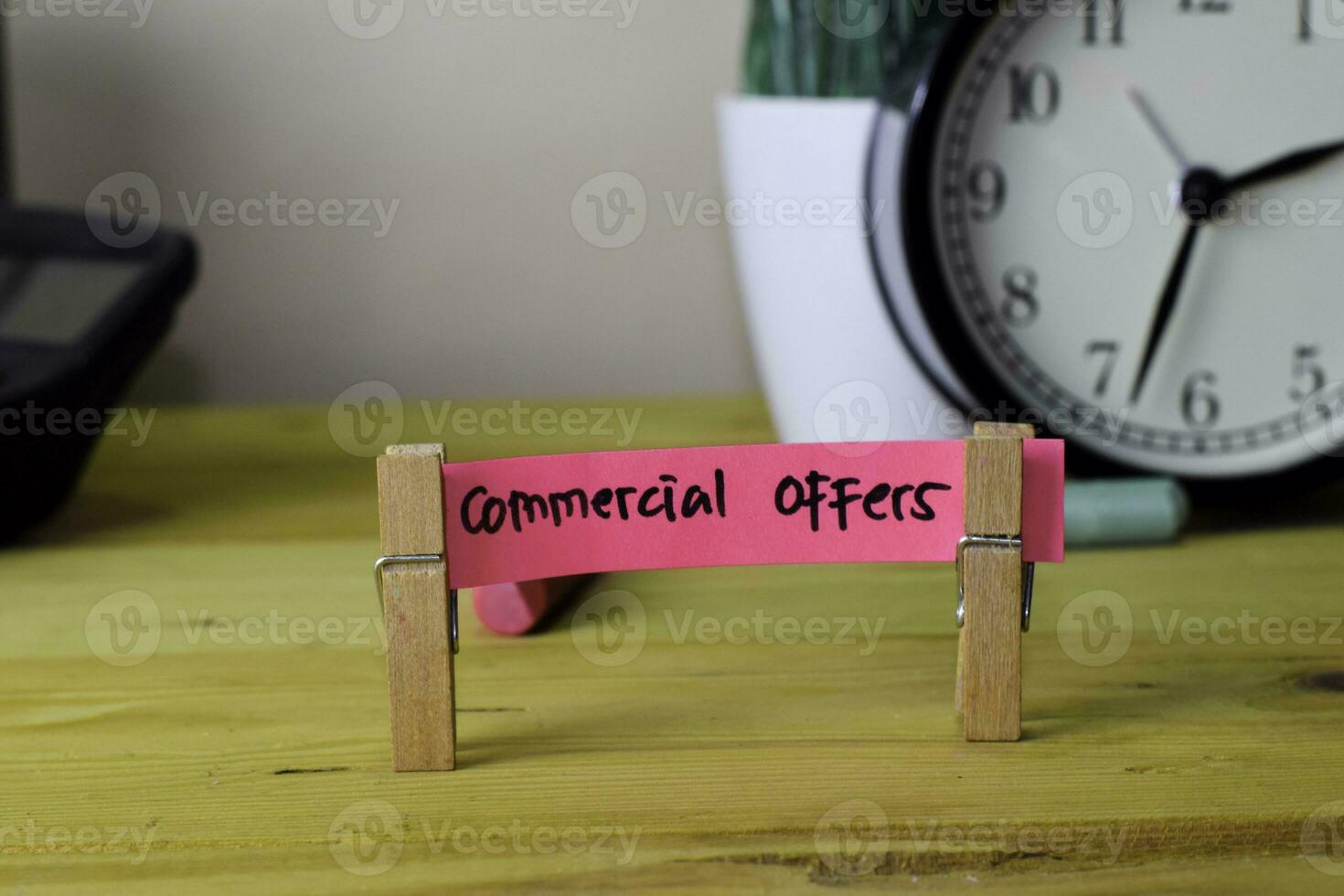 Commercial Offers. Handwriting on sticky notes in clothes pegs on wooden office desk photo