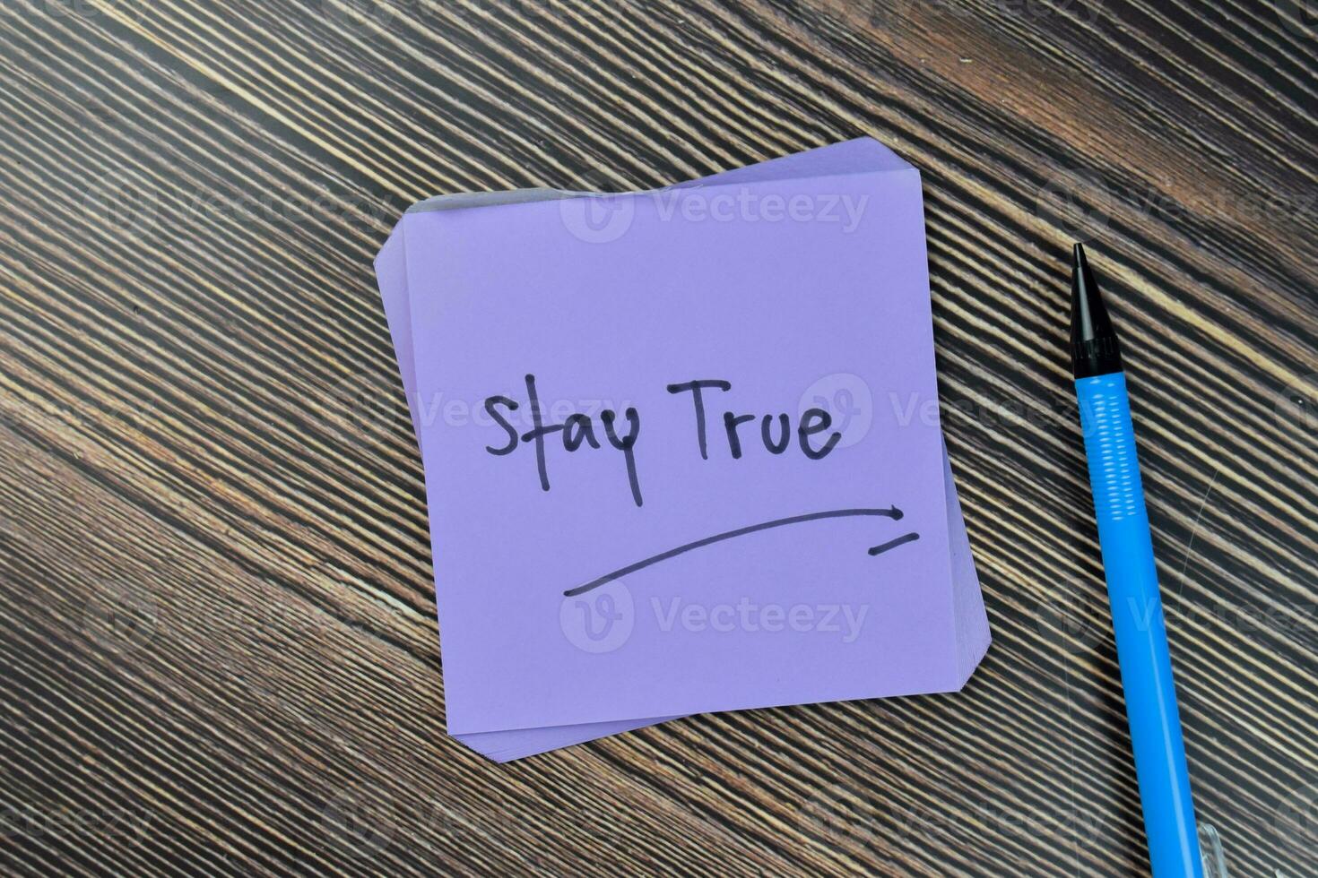 Concept of Stay true write on sticky notes isolated on Wooden Table. photo