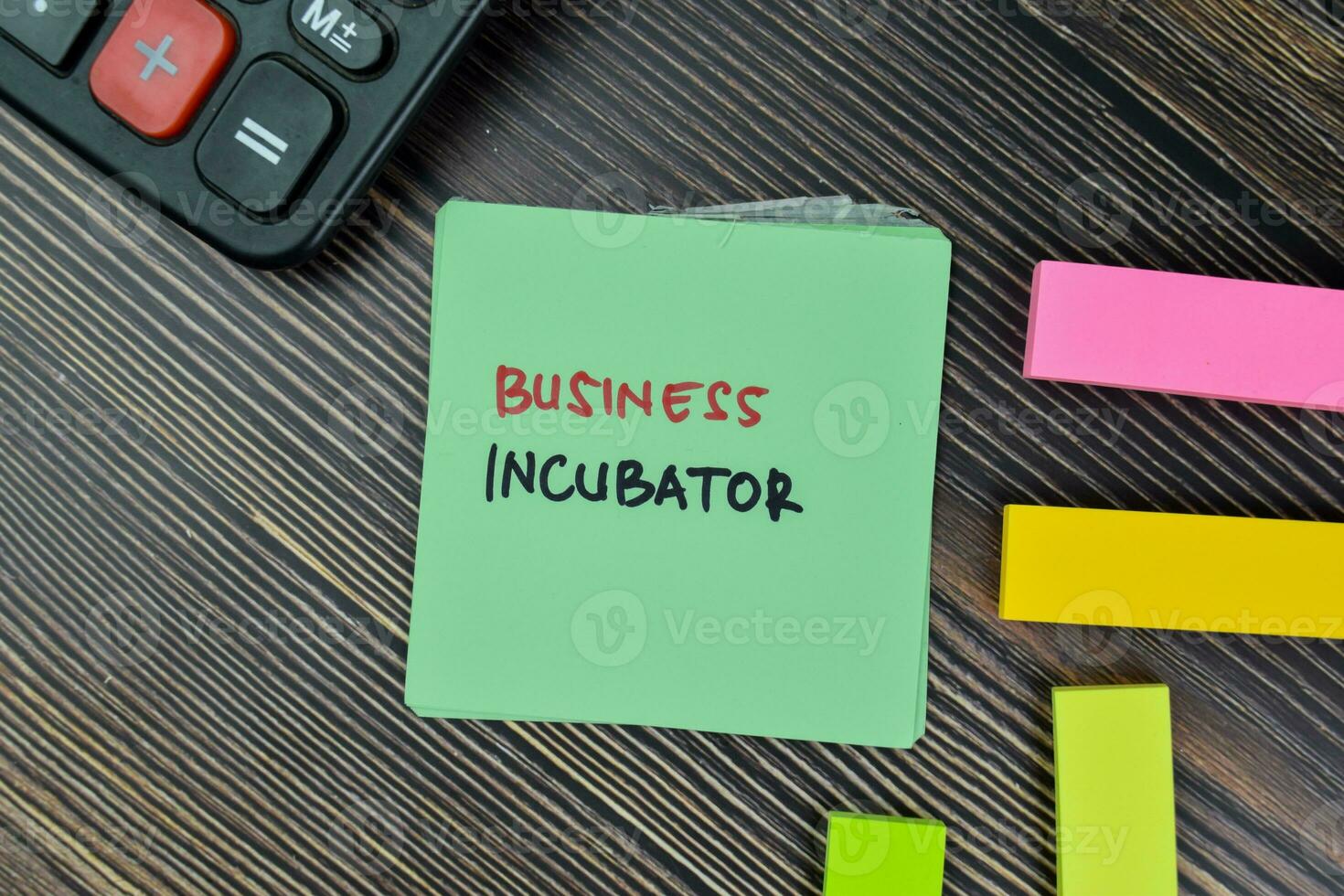 Business Incubator write on sticky notes isolated on Wooden Table. photo