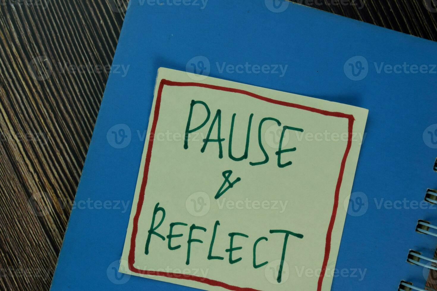 Pause and Reflect write on sticky notes isolated on Wooden Table. photo