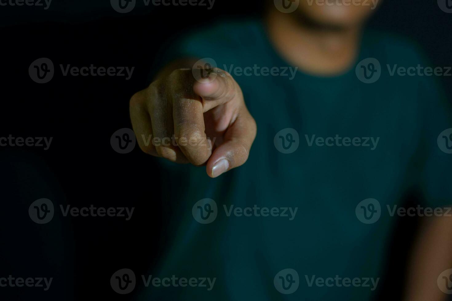 Young man showing finger it means make your choice on dark black background. selective focus on finger photo