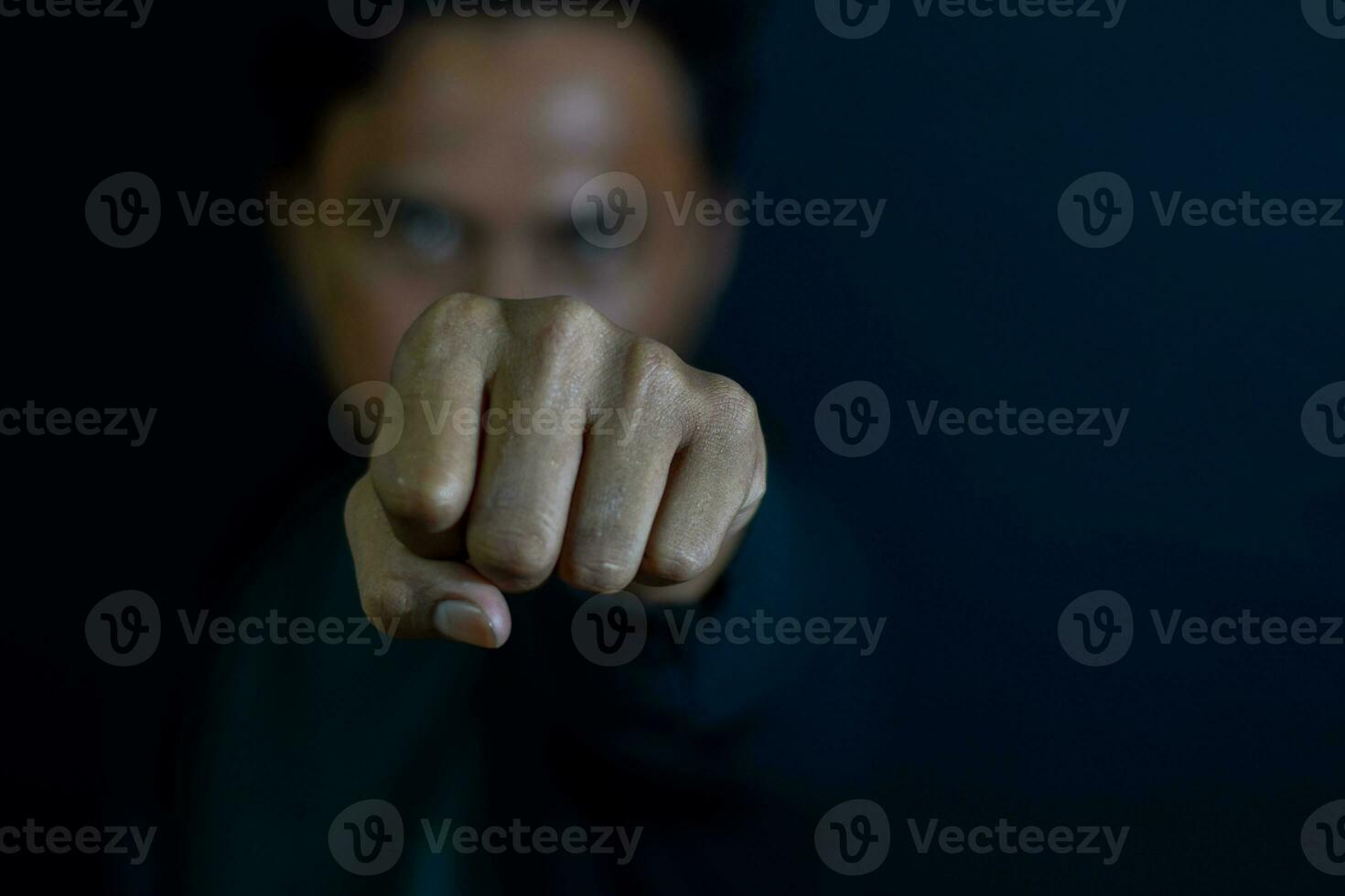 Young man showing finger it means serious or boxing, fighting concept on dark black background. selective focus on finger photo