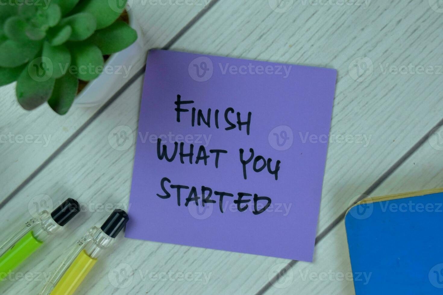 Concept of Finish What You Started write on sticky notes isolated on Wooden Table. photo