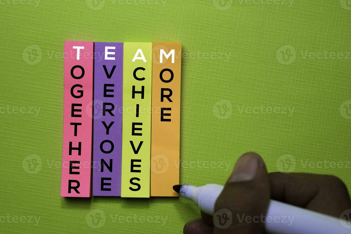 Together, Everyone, Achieves, More text on sticky notes isolated on green desk. Mechanism Strategy Concept photo