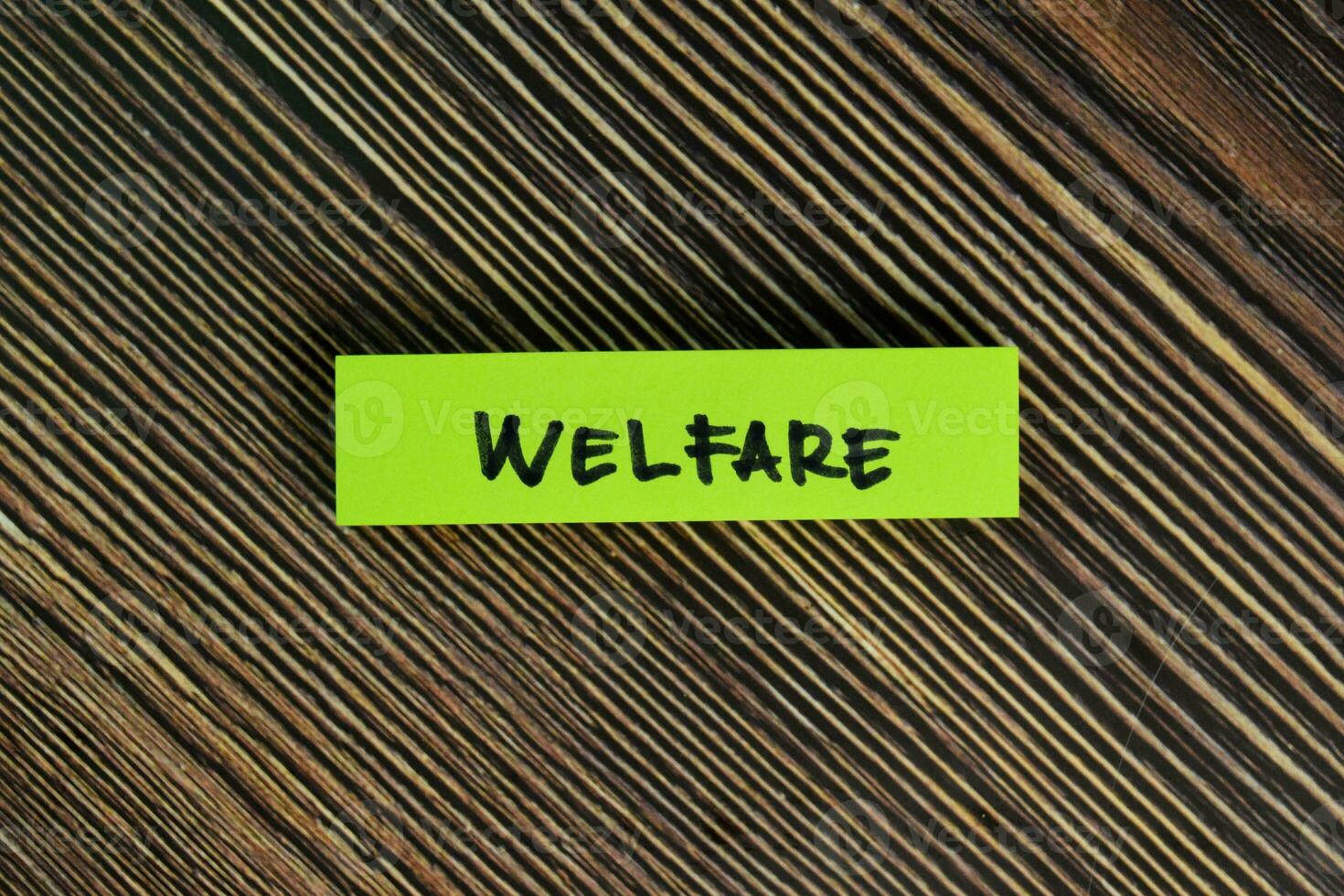 Welfare write on sticky notes isolated on Wooden Table. photo