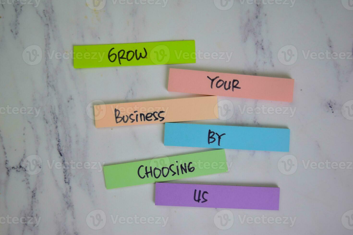 Grow Your Business By Chossing Us write on sticky notes isolated on Wooden Table. photo