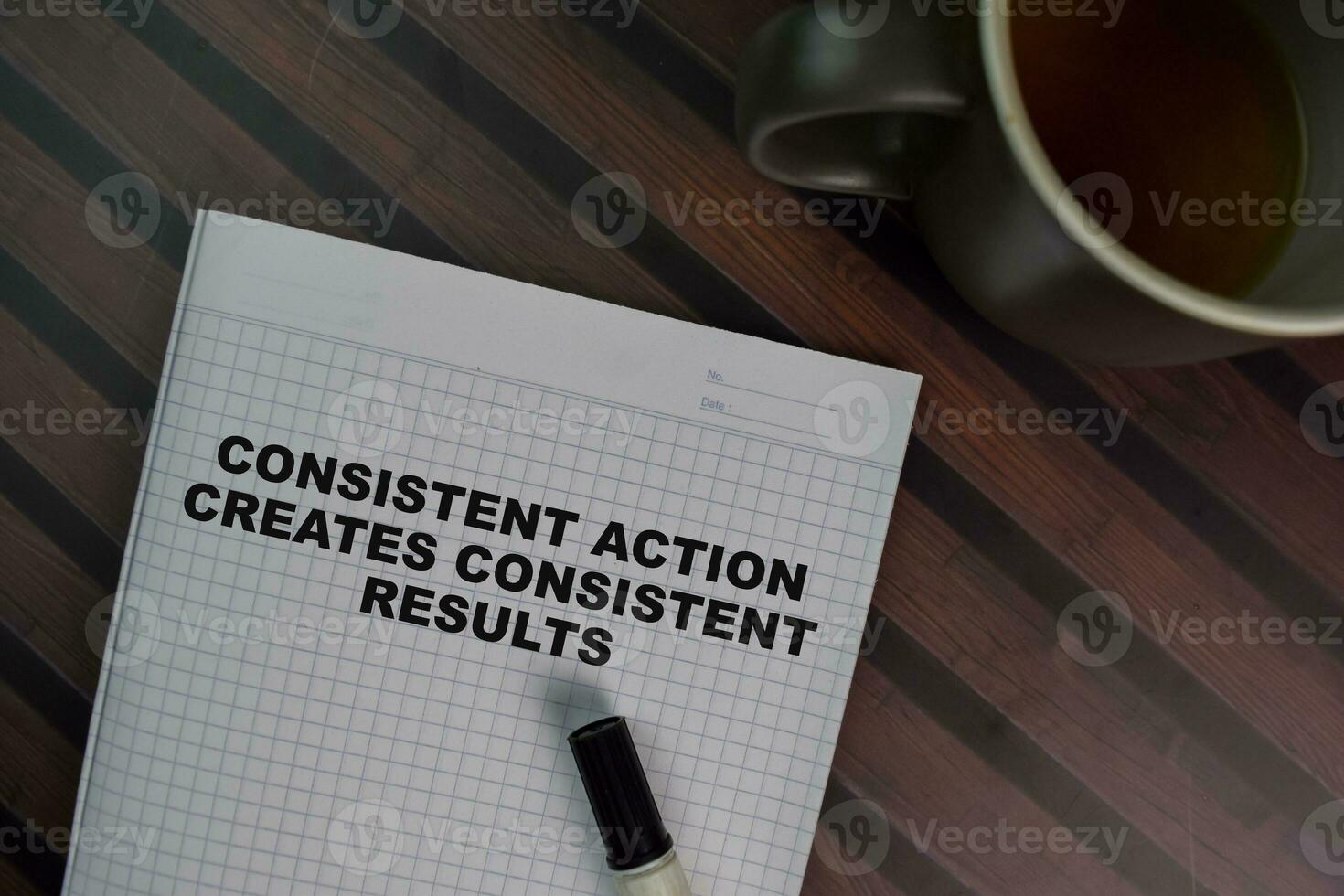 Consistent Action Creates Consistent Results write on a book isolated on Wooden Table. photo