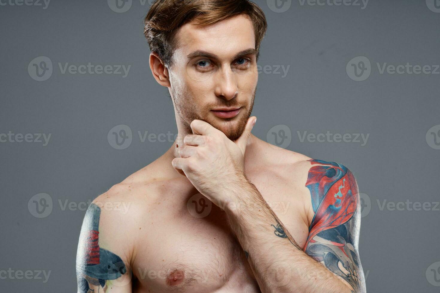 portrait of young man with tattoos on gray background and beautiful face model cropped view photo