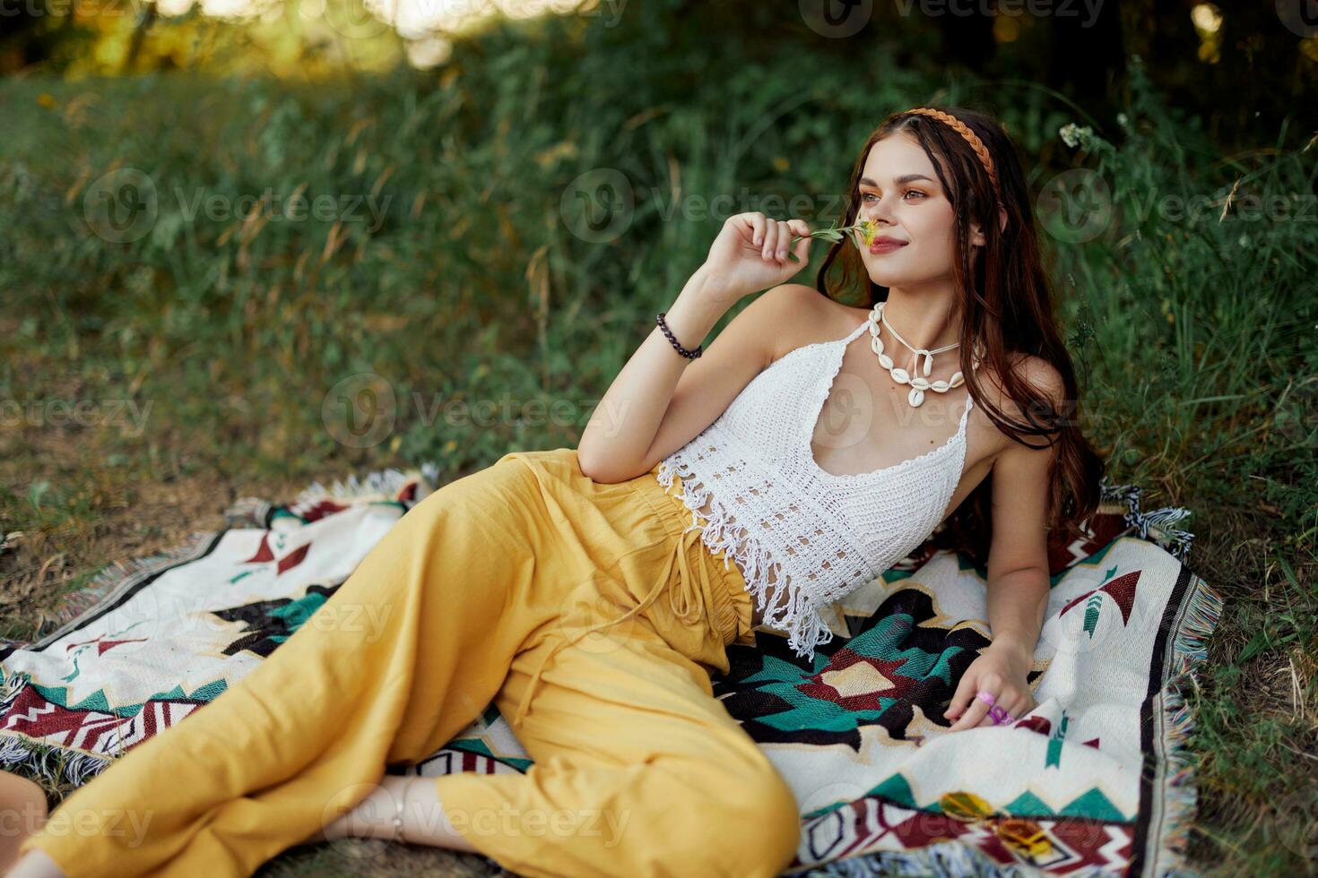 joven hermosa hippie mujer acostado en el suelo en naturaleza en el otoño en eco ropa en amarillo pantalones en el puesta de sol ligero foto