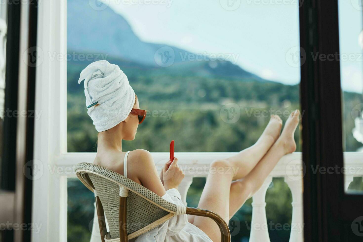 Portrait of gorgeous woman with a red mobile phone sitting on the balcony Mountain View photo