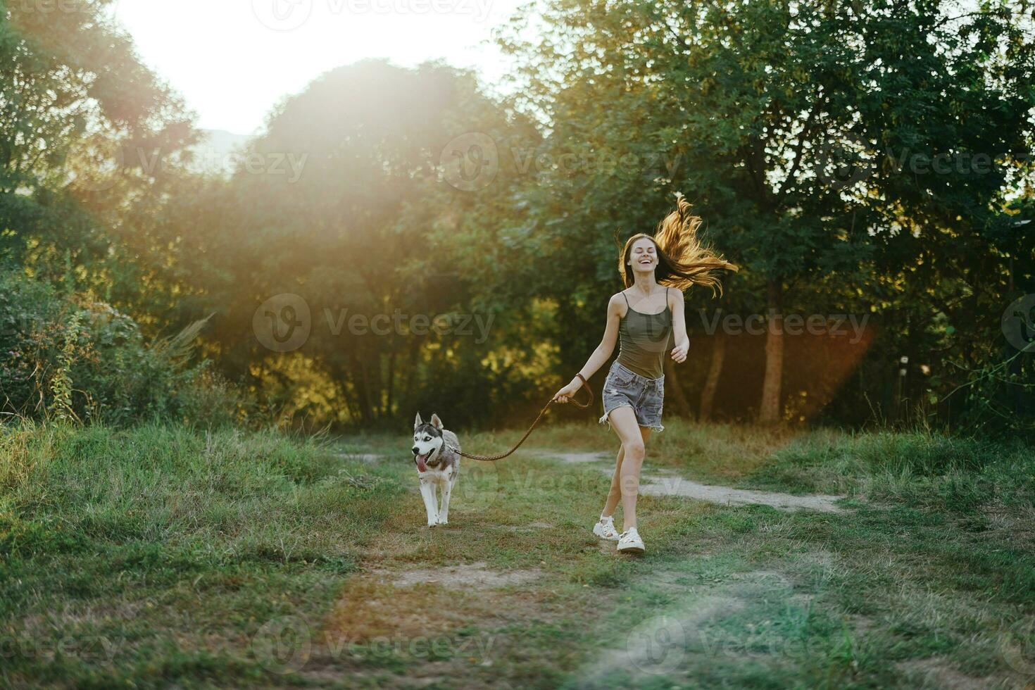 Woman and her husky dog happily running through the grass in nature in the park smile with teeth fall walk with pet, traveling with a dog friend photo