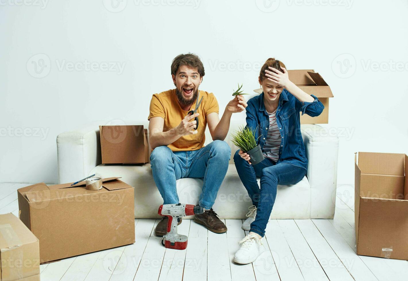 Man and woman sit on white couch boxes with moving lifestyle things photo