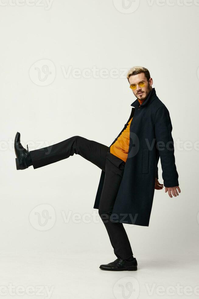 energetic man in pants and coat orange sweater light background model photo