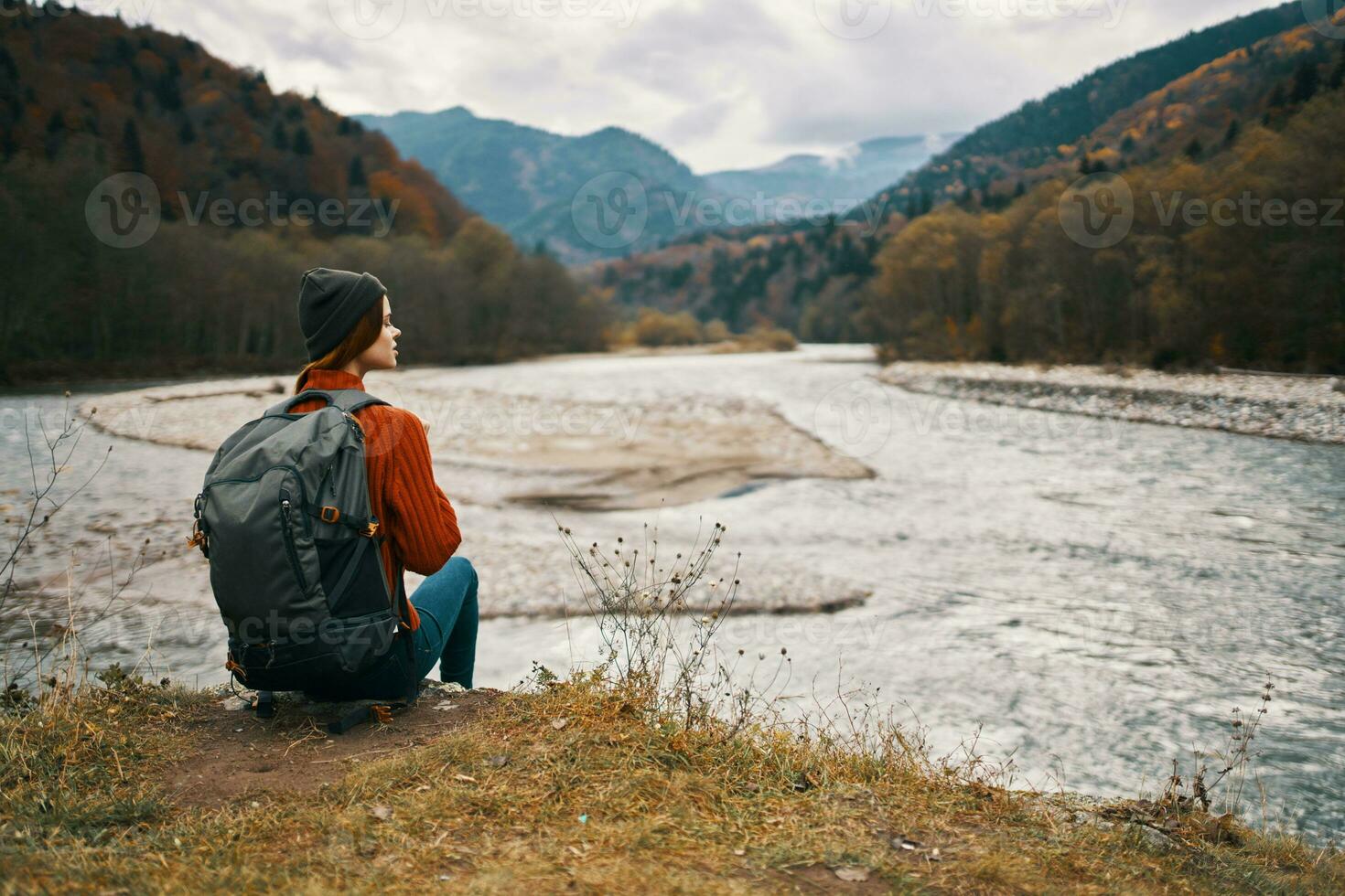 traveler sits on the banks of the river in the mountains in nature back view photo