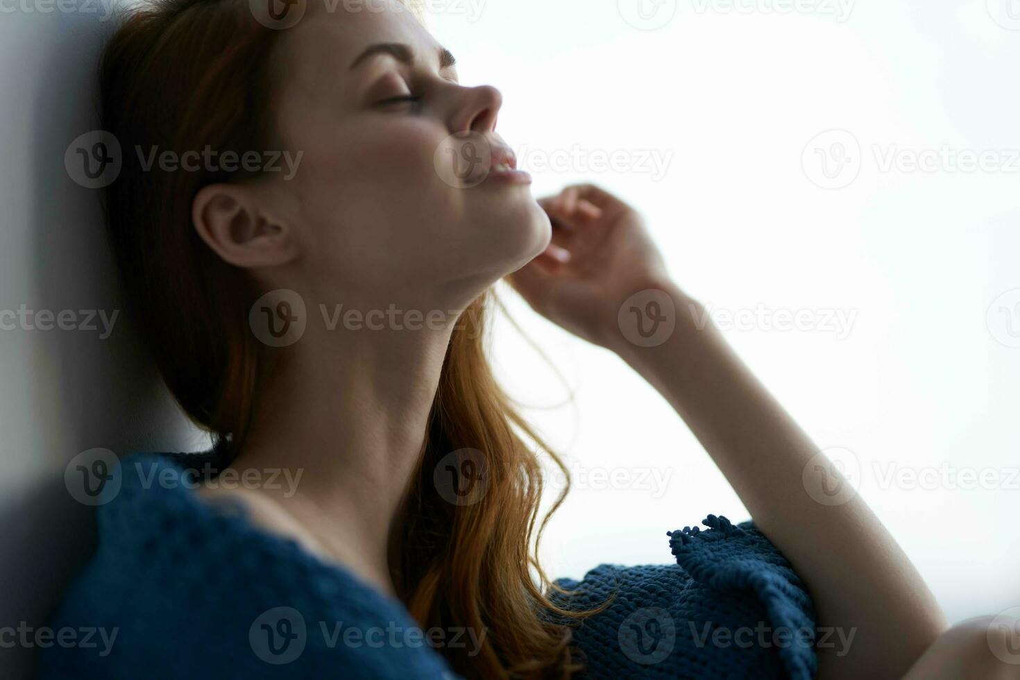 pretty woman sitting near the window with a blue plaid rest photo