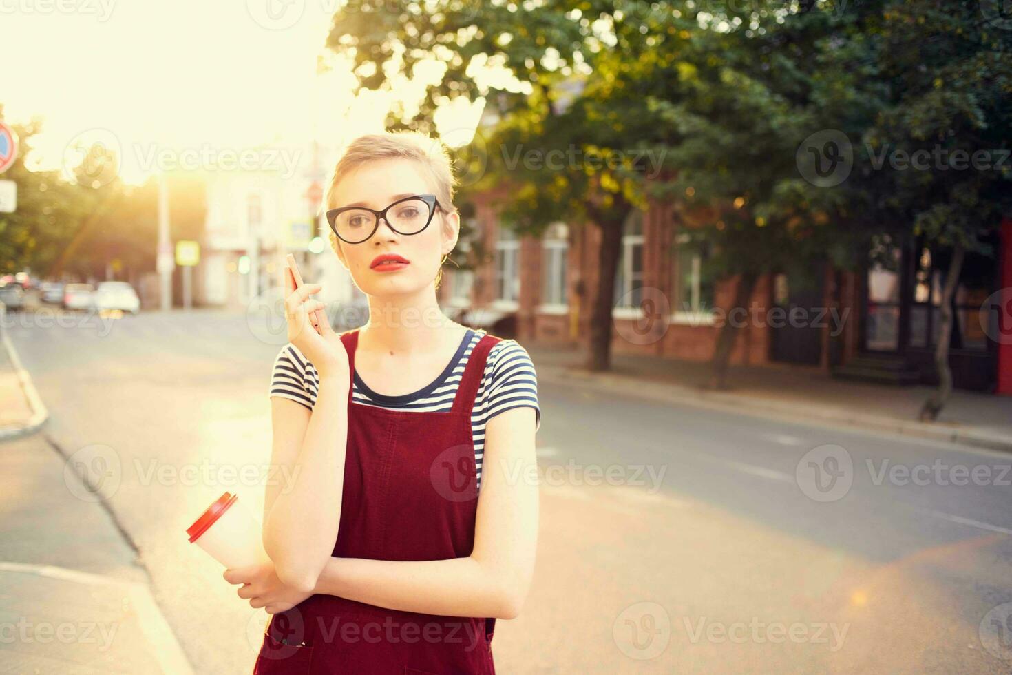 woman with short hair on the street talking on the phone a cup of drink photo
