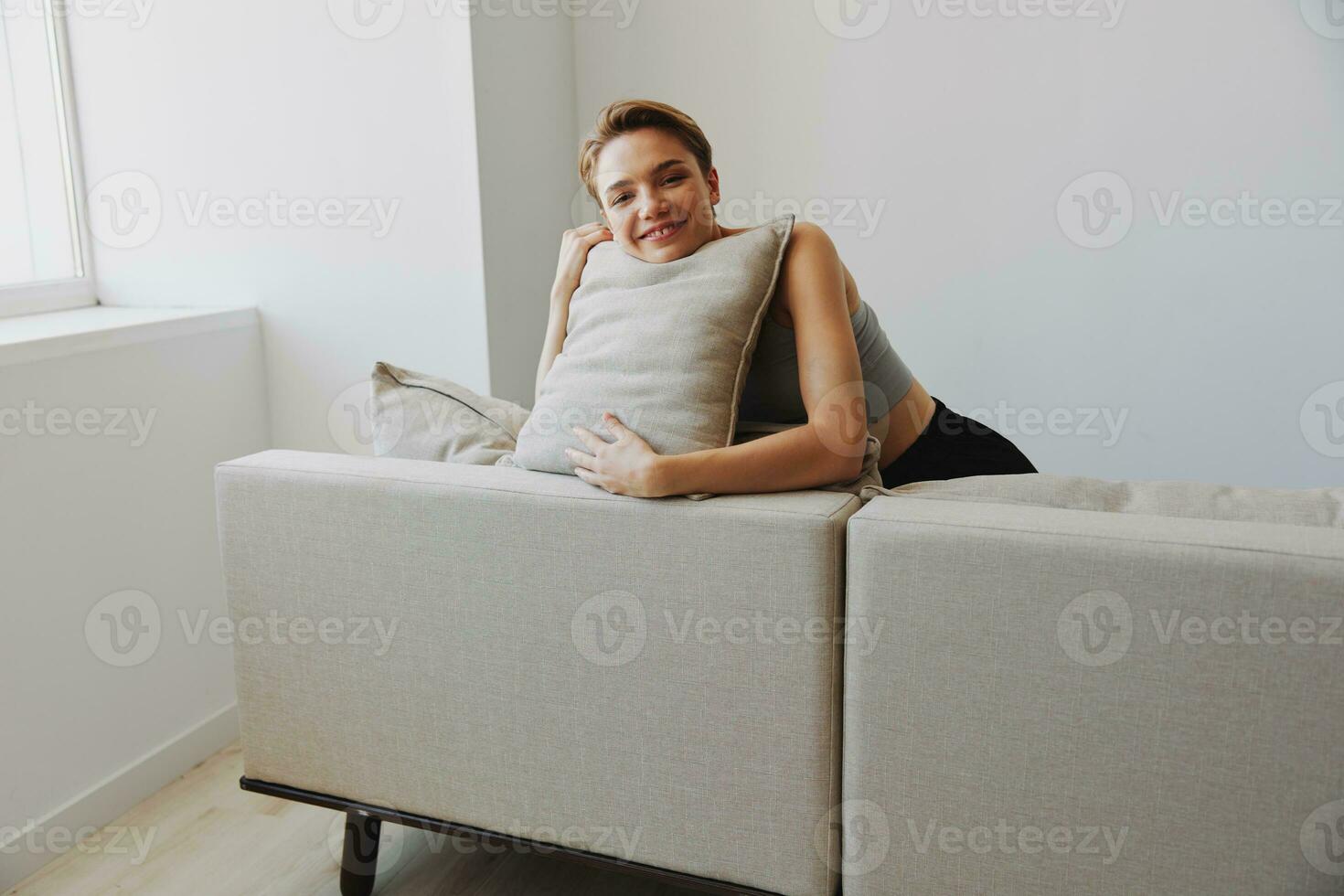 contento mujer sonrisa acostado a hogar en el sofá relajante en un fin de semana a hogar con un corto Corte de pelo pelo sin filtros en un blanco fondo, gratis Copiar espacio foto