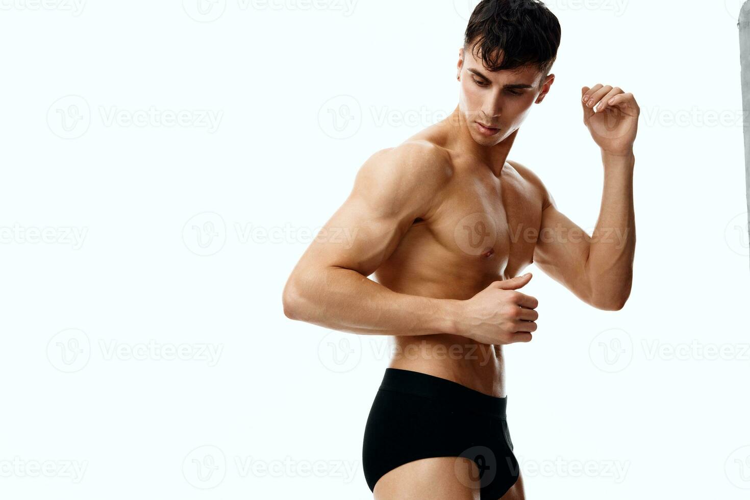 sexy Atletas con un desnudo torso gesticular con su manos en un ligero antecedentes Copiar espacio foto
