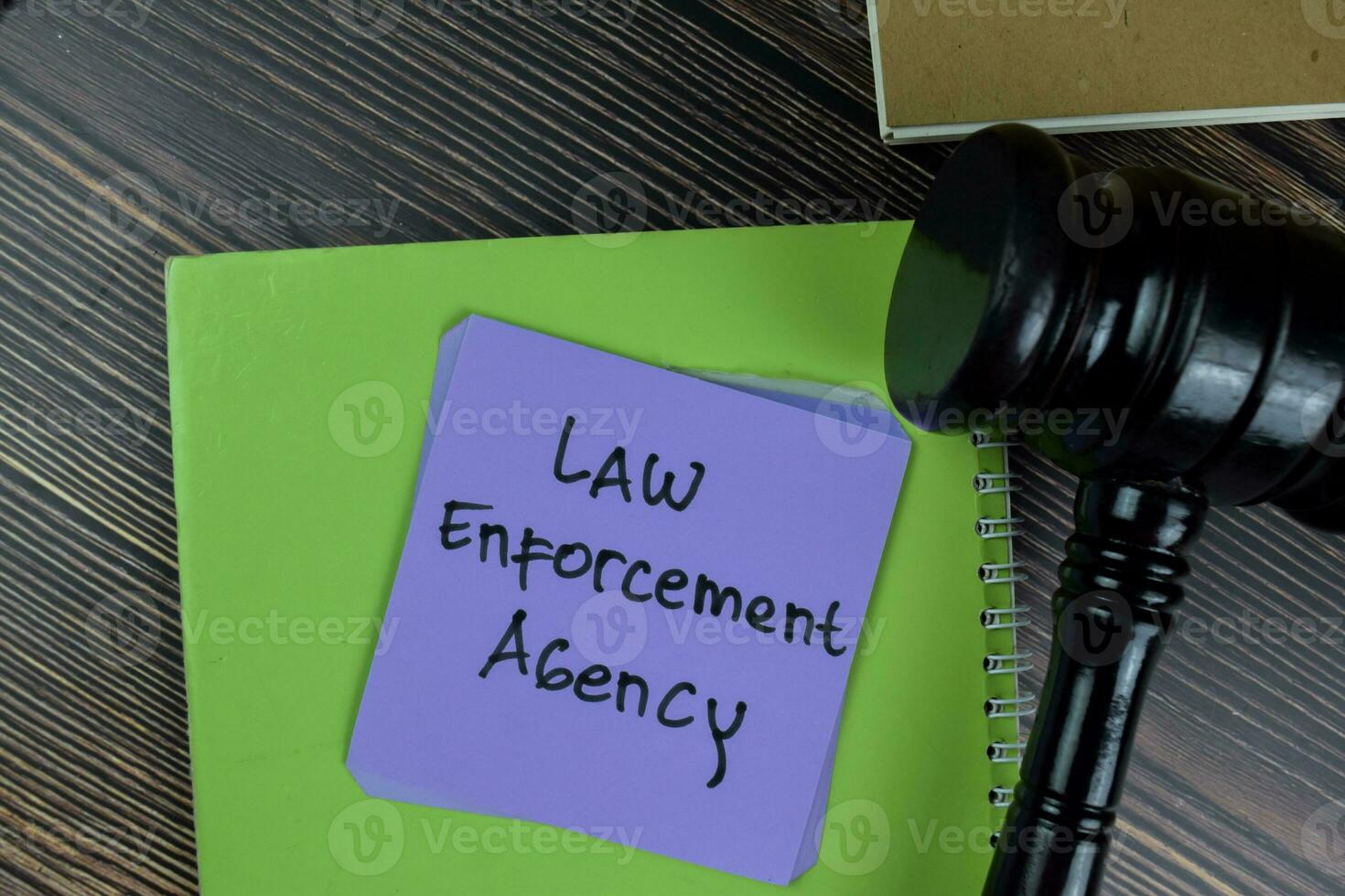 Concept of Law Enforcement Agency write on sticky notes with gavel isolated on Wooden Table. photo