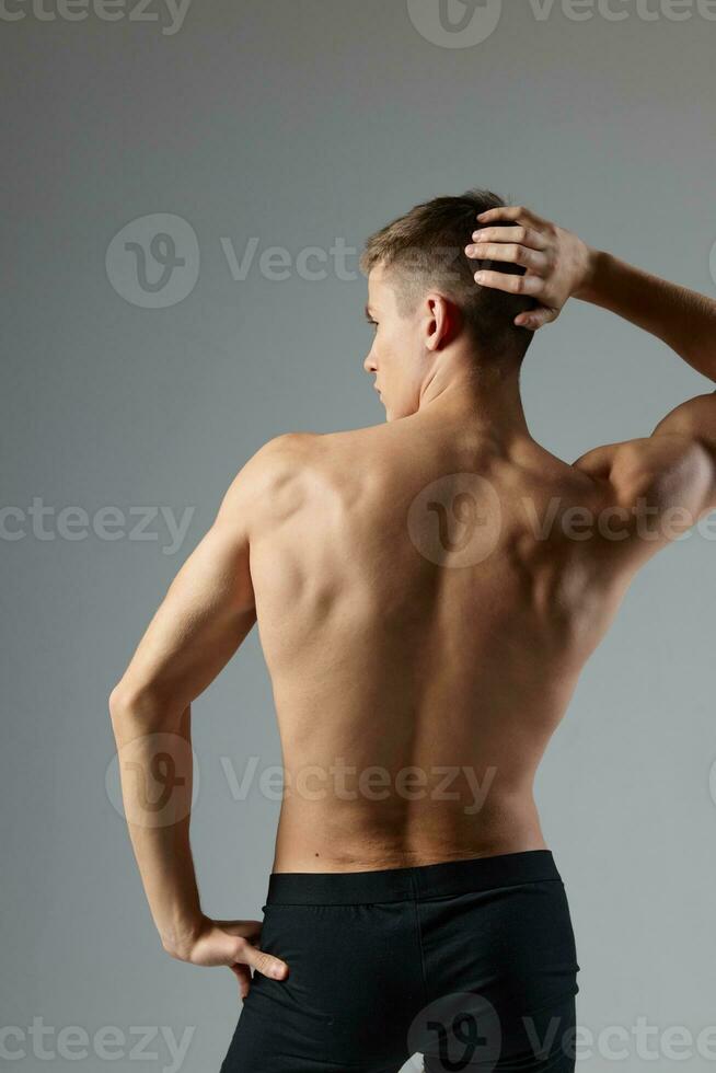 athletic male athlete posing with pumped body back view isolated