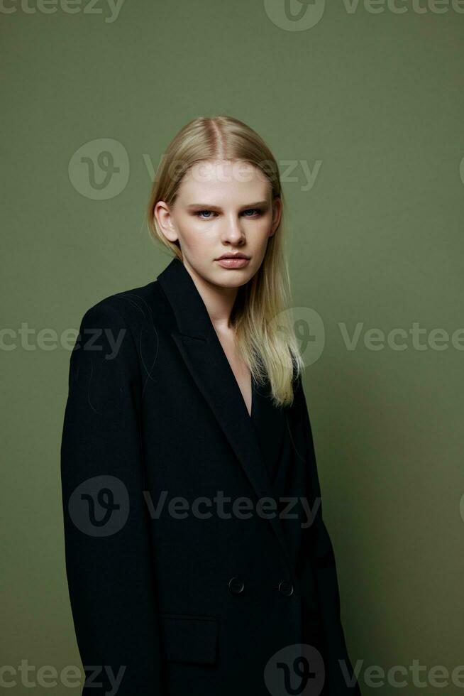 A strict serious elegant lady looks into the camera posing on a green background photo