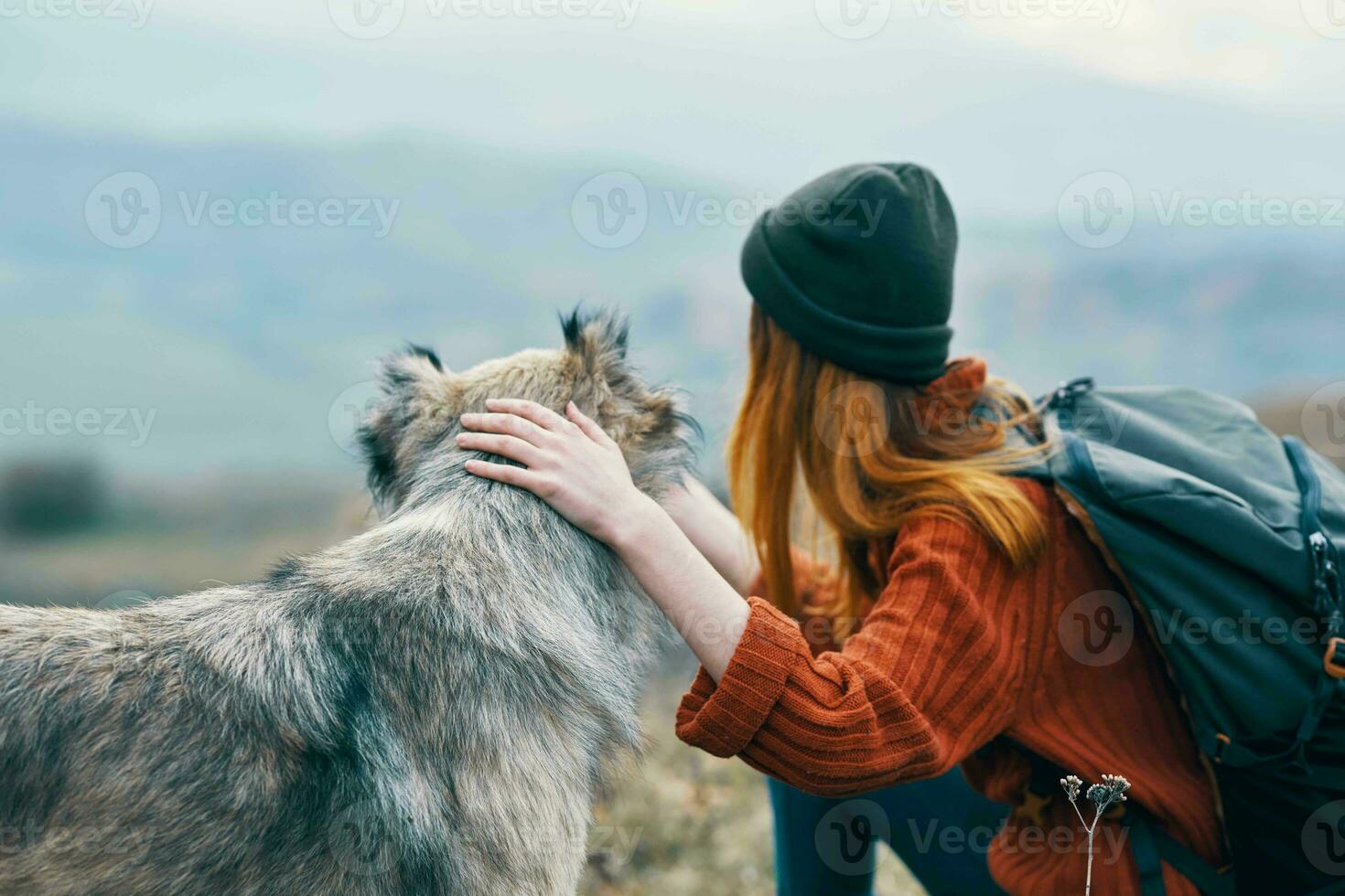 woman tourist with backpack playing with dog on nature travel photo