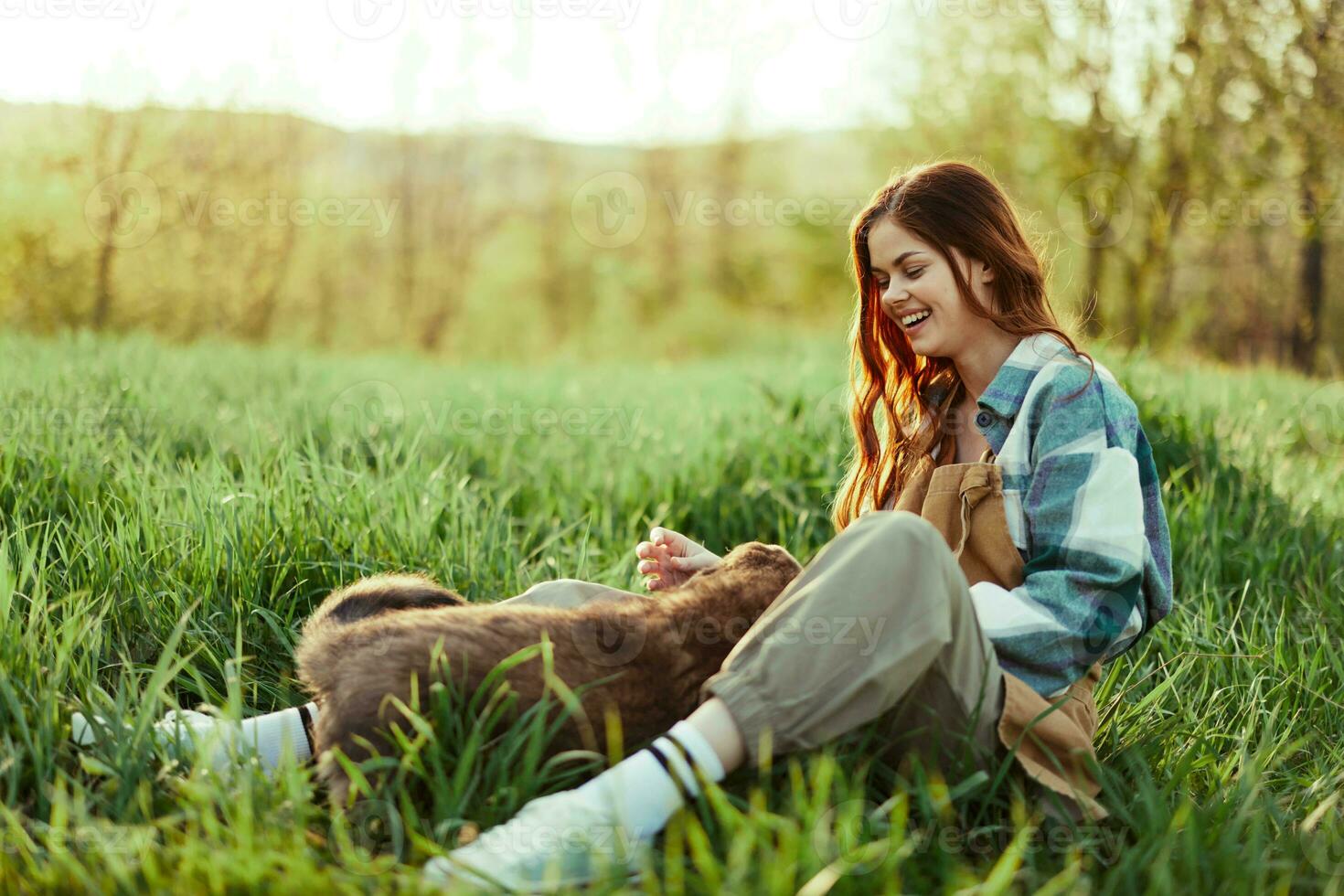 Woman happily smiling at playing with her little dog outdoors on fresh green grass in the summer sunshine her and her dog's health, Health Concept and timely treatment for insects ticks and tick fleas photo