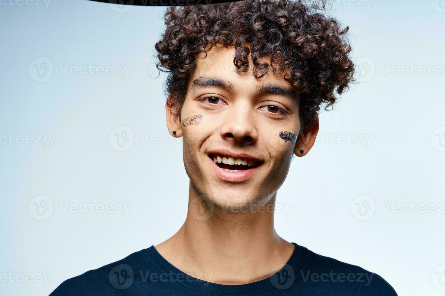 Cheerful man with curly hair cosmetics on face clean skin photo