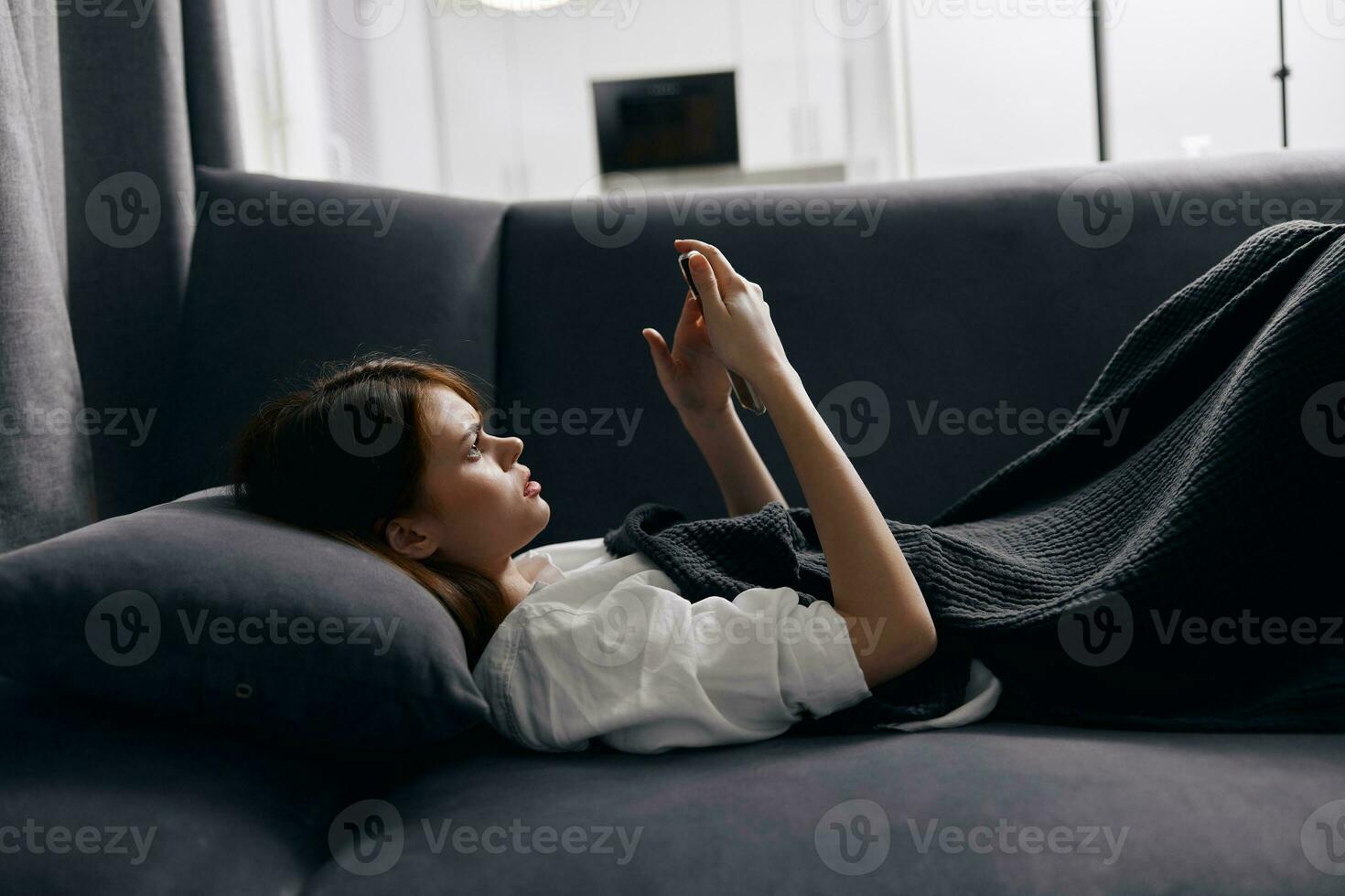 woman resting lying on couch with mobile phone in hand cropped view photo